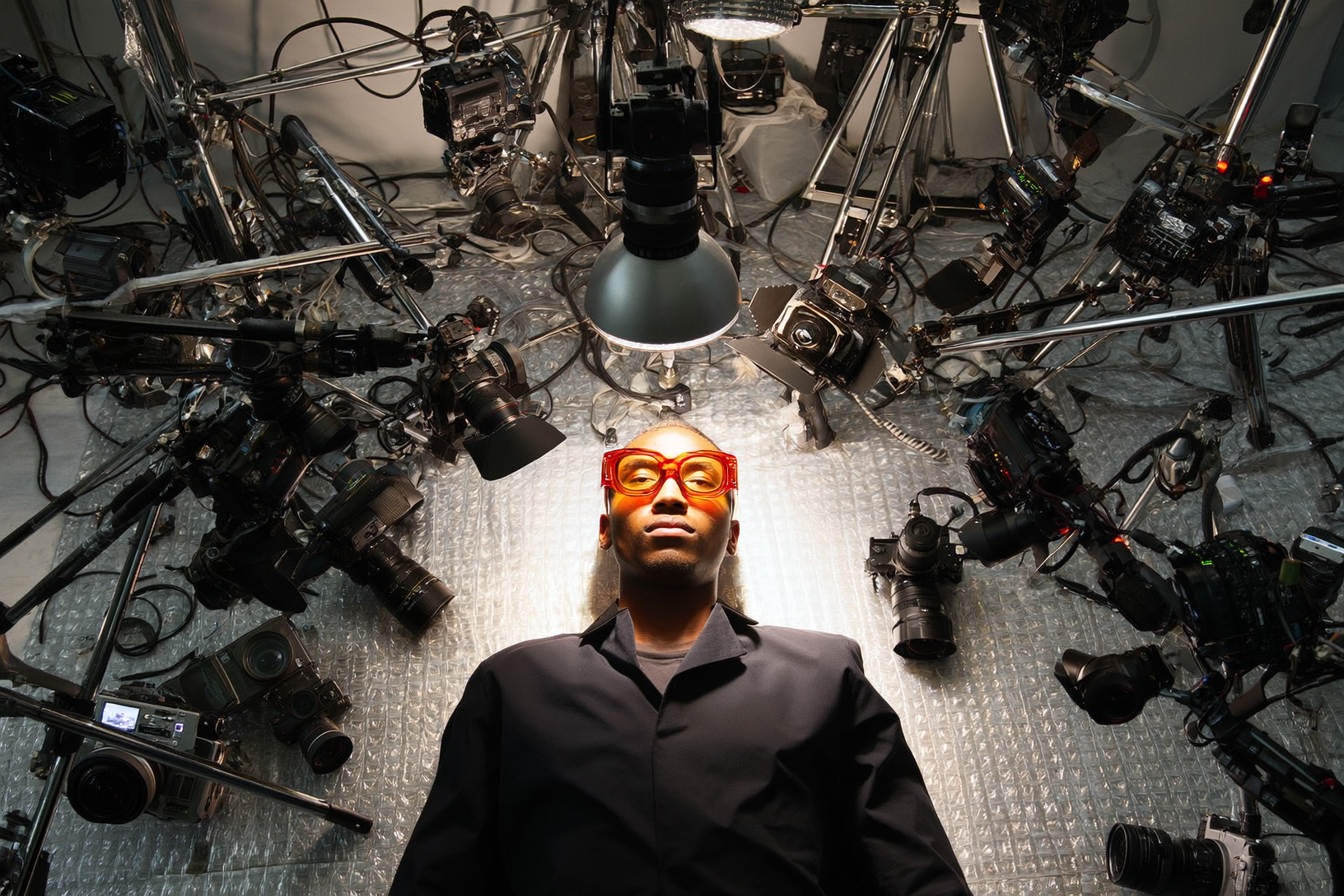 modello sdraiato con occhiali da sole e molte attrezzature fotografiche intorno